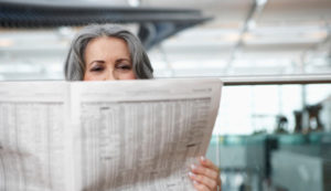 woman-reading-newspaper-airport-628x363